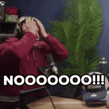 a man is sitting in front of a microphone with his hands on his head and the words nooooo on the bottom right