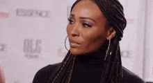 a woman with braids is wearing hoop earrings and a black top .