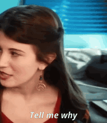 a woman says tell me why in front of a blue window