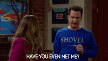 a man in a blue shovel sweater is talking to a woman