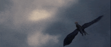 a dragon is flying through a cloudy sky with wings spread .