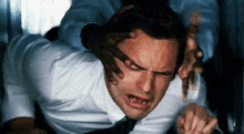 a man in a white shirt and tie is laying on his back with his mouth open