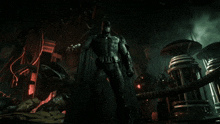 a statue of batman standing in a dark room with a red light behind him