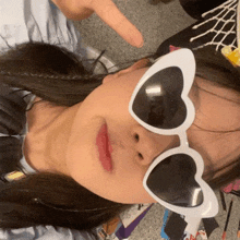 a woman wearing a pair of heart shaped sunglasses is pointing at the camera .