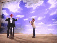 a man in a tuxedo and red hat is standing next to a girl in a white shirt
