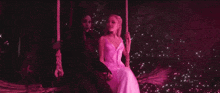two women are sitting on a swing in a dark room