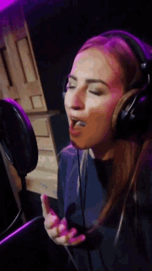 a woman is singing into a microphone with headphones on
