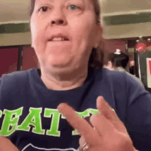 a woman in a blue shirt with the word eat on it is making a funny face .
