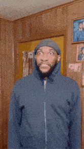 a man with a beard wearing a hoodie is standing in a room