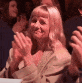 a woman in a tan jacket is clapping her hands