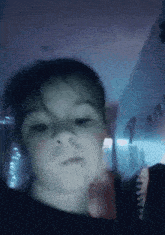 a close up of a child 's face in a dark room with a blue background