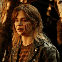 a woman in a leather jacket has blood on her face .