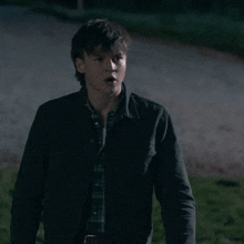 a young man in a plaid shirt and a black jacket