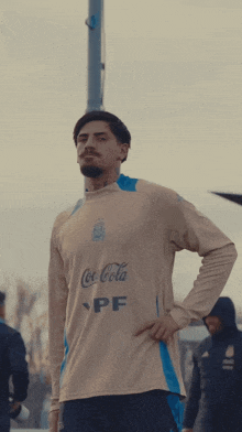 a man wearing a coca cola ypf jersey stands with his hand on his hip