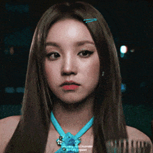 a close up of a woman 's face with a blue necklace