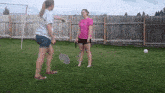 a woman in a pink shirt is holding a badminton racquet
