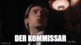 a man in a suit and tie is looking up with his mouth open and the words der kommandar written above him .
