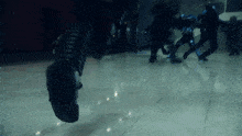 a person 's foot is visible in a blurry photo of a group of people running on a tiled floor