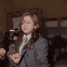 a woman in a suit and tie is dancing in front of a group of people