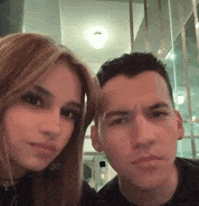 a man and a woman are sitting next to each other and looking at the camera .