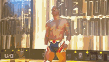 a man in a wrestling outfit is standing in front of a wall that says freedom