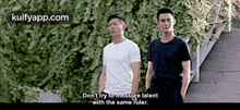 two men are standing next to each other in front of a hedge and a staircase .