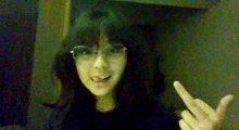 a young woman wearing glasses is giving the middle finger .