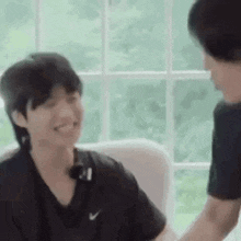 two men are sitting next to each other on a couch and holding hands .