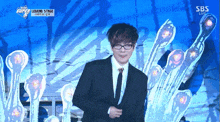 a man in a suit and tie is standing in front of a sbs logo