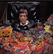 a man sits in a chair surrounded by candy including reeses and jolly rancher