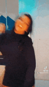 a woman in a black turtleneck is laughing and dancing .