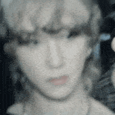 a blurry photo of a woman 's face with a necklace around her neck