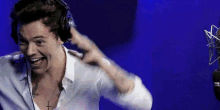 harry styles is wearing headphones and making a funny face .