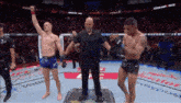 a referee stands between two fighters in a boxing ring .