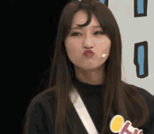 a woman with long hair is making a funny face with her mouth open and a microphone in her mouth .