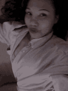 a woman is taking a selfie while wearing a white shirt .