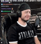 a man wearing headphones and a black shirt that says ' we lost to the zone that aren 't here '