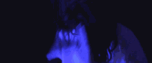 a person wearing glasses and a white shirt is dancing in a dark room with blue lights .