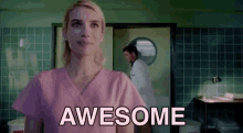 a woman in a pink scrub top is standing in a hospital room with the words `` awesome '' written on her face .