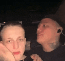 two men are sitting next to each other and one is wearing ear buds
