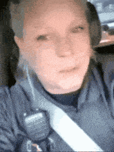 a woman in a police uniform is sitting in a car wearing a seat belt .