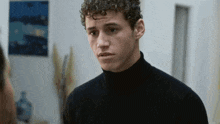 a young man with curly hair wearing a black turtleneck sweater