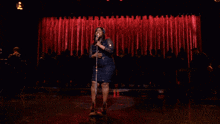 a woman is singing into a microphone on a stage