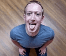 a man sticking his tongue out while wearing a blue shirt