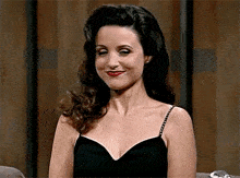 a woman in a black dress is smiling and looking to the side