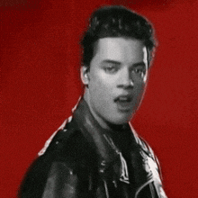 a black and white photo of a young man wearing a leather jacket