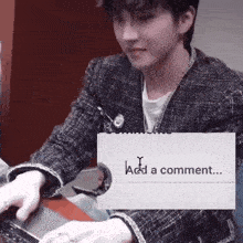 a man is typing on a laptop with a sign that says add a comment