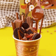 a cup filled with ice cream oreos cinnamon sticks and caramel