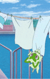 a frog is hanging upside down on a clothes line near a body of water