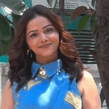 a woman wearing a blue shirt and a tie smiles for the camera